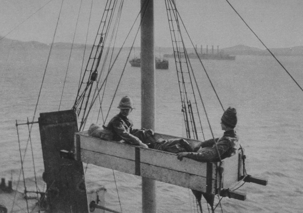 A Box Stretcher Hoisting Wounded Soldiers On To A Red Cross Ship